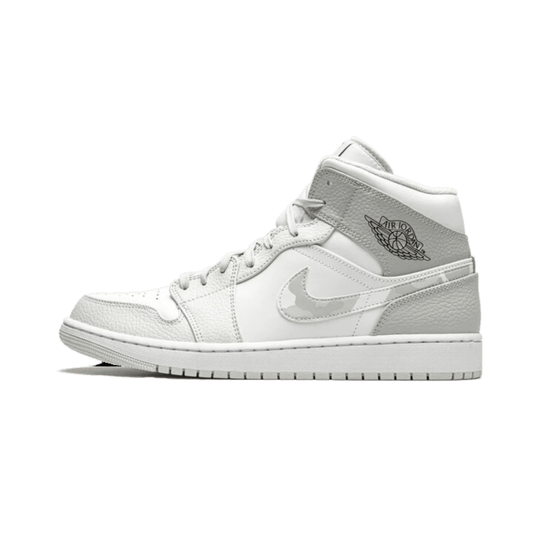 Elegante grijze Air Jordan 1 Mid sneakers op een groene achtergrond. Een klassiek Nike ontwerp met een suède bovenwerk en het iconische Jumpman-logo op de zijkant. Deze sneakers bieden een comfortabele pasvorm en stijlvolle uitstraling.