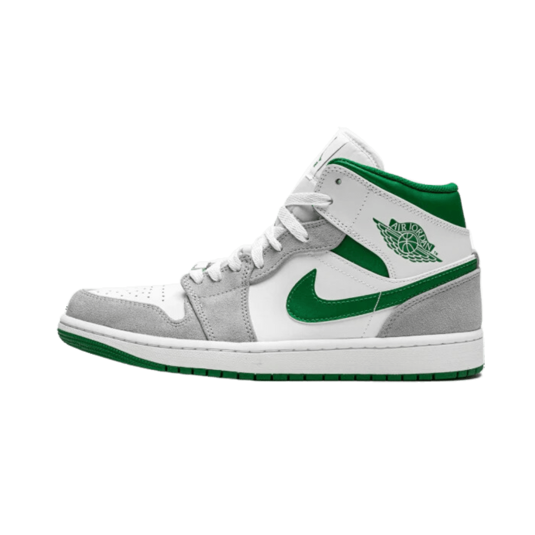 Grijze en groene Air Jordan 1 Mid sneakers, geplaatst op een groene achtergrond. De sneakers vertonen een klassiek ontwerp met het Nike-logo en de kenmerkende Jumpman-branding. Deze high-top sneakers zijn gemaakt van verschillende materialen, waaronder suède en leer, en bieden een premium look en feel.