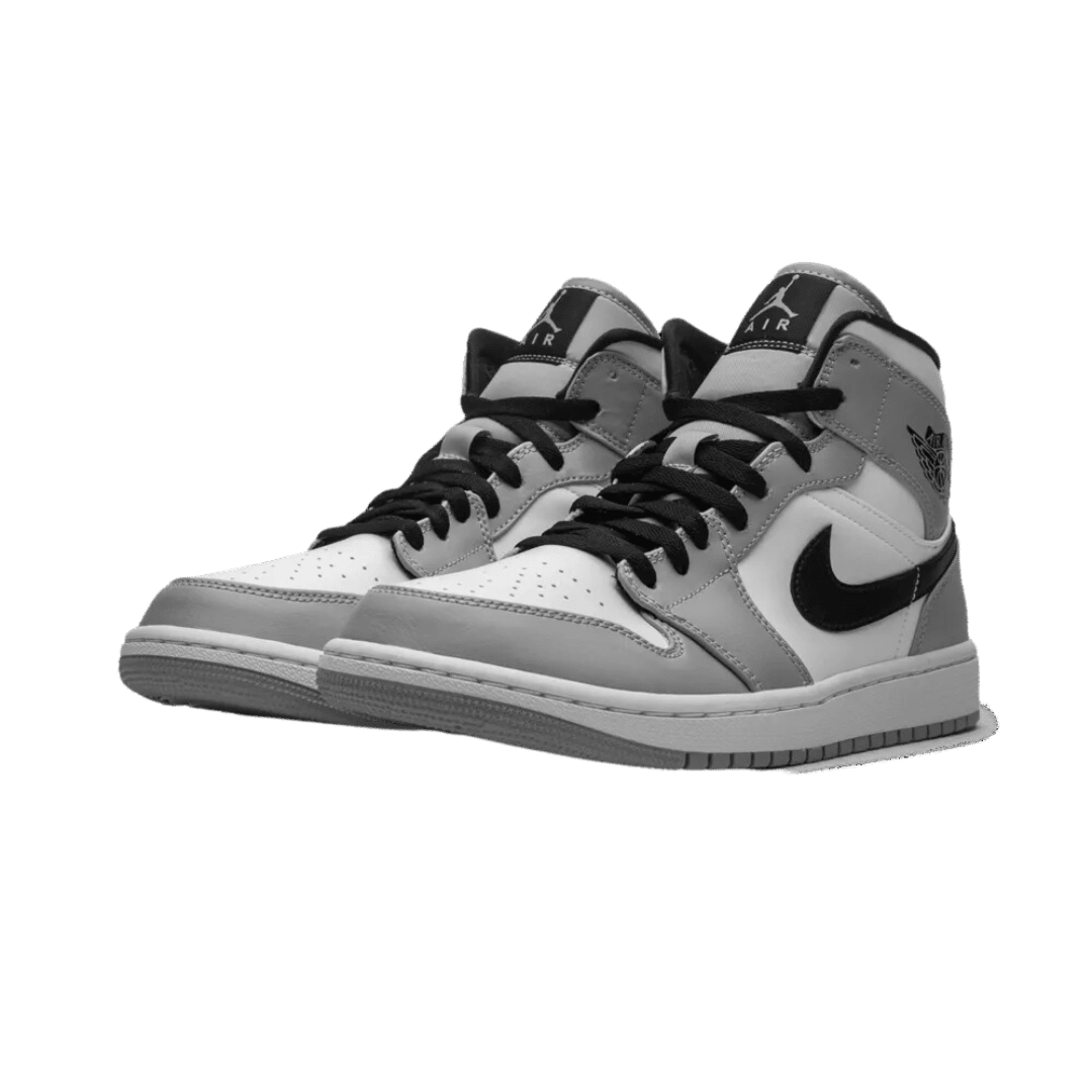 Klassieke lichtgrijze Nike Air Jordan 1 Mid-sneakers op een donkergroene achtergrond