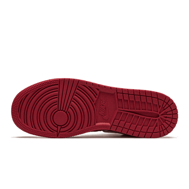 Rode Air Jordan 1 Mid SE sneakers met een gestructureerd quilted patroon op de zool, tegen een groene achtergrond.