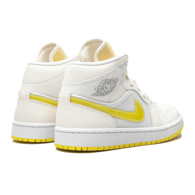 Elegante Nike Air Jordan 1 Mid SE Voltage Yellow sneakers op een groene achtergrond. Deze witte hoge sneakers met gele accenten zijn een opvallende toevoeging aan je garderobe.