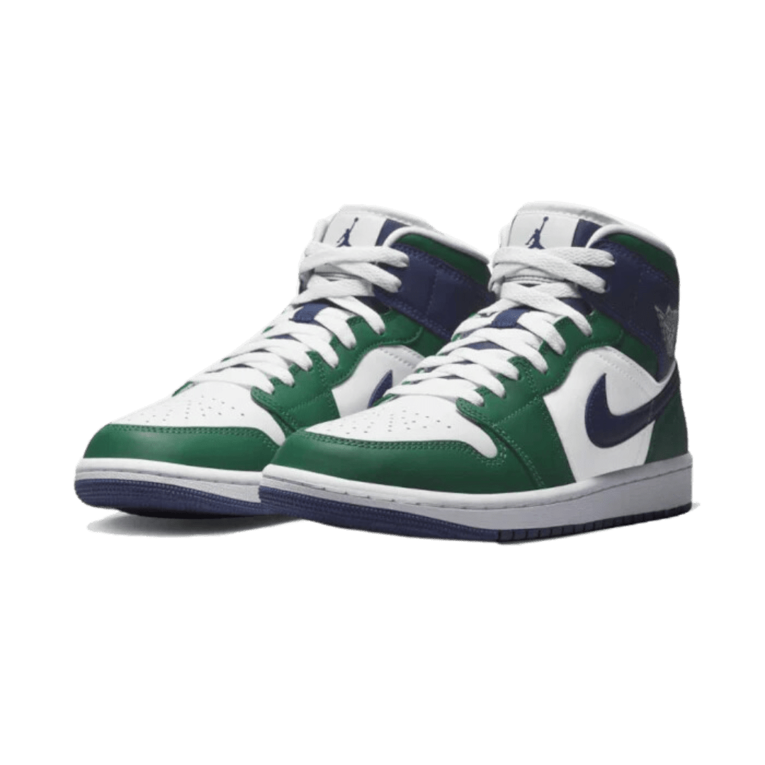 Elegante Air Jordan 1 Mid Seahawks sneakers op een groene achtergrond. De sneakers hebben een wit, groen en navy ontwerp met het kenmerkende Jordan-logo. Dit model is een populaire versie binnen de Jordan-collectie.