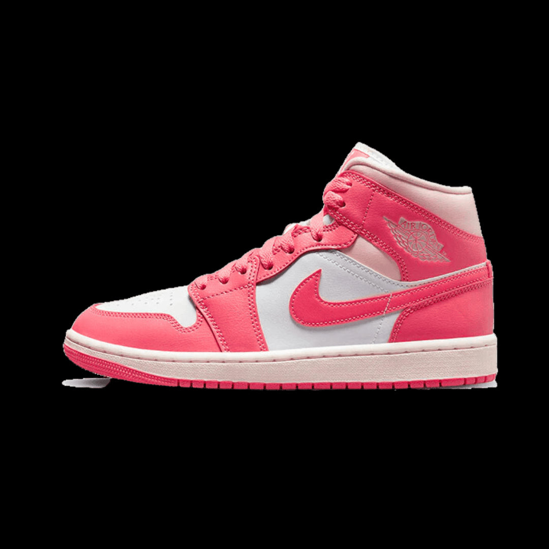 Stylvolle roze en witte Nike Air Jordan 1 Mid sneakers met 'Strawberries and Cream'-design, geplaatst tegen een groene achtergrond.