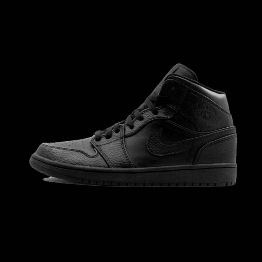 Zwarte Air Jordan 1 Mid sneakers op een groene achtergrond. Deze sportieve schoenen, ontworpen door Nike, hebben een premium lederen bovenkant en een vetersluiting voor een stijlvolle en comfortabele pasvorm.
