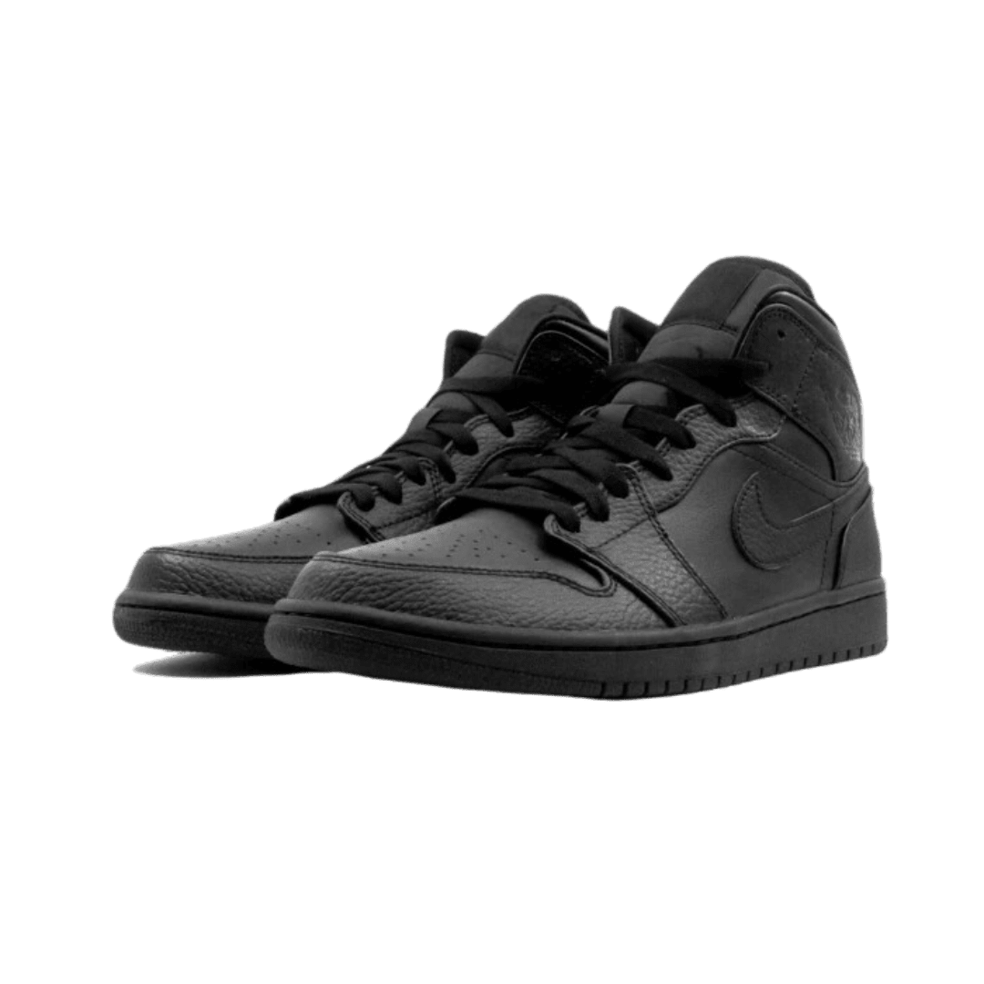 Zwart lederen Air Jordan 1 Mid sneakers op een groene achtergrond