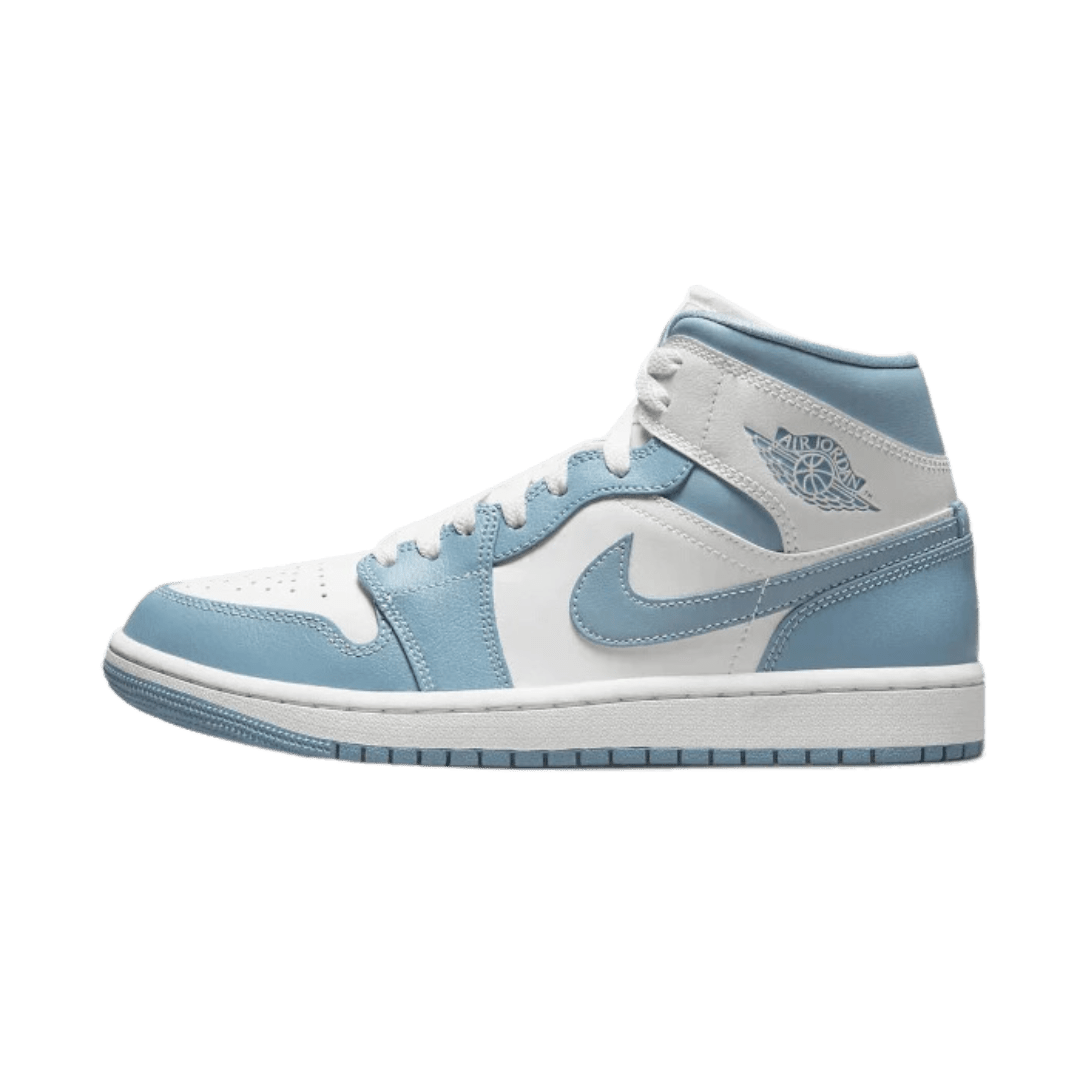 Elegante sneakers Air Jordan 1 Mid UNC (2022) op groene achtergrond. De sneakers hebben een lichtblauwe en witte kleurencombinatie met Nike-logo's op de zijkant. Dit zijn stoere, comfortabele en stijlvolle Jordan-sneakers voor dagelijks gebruik.