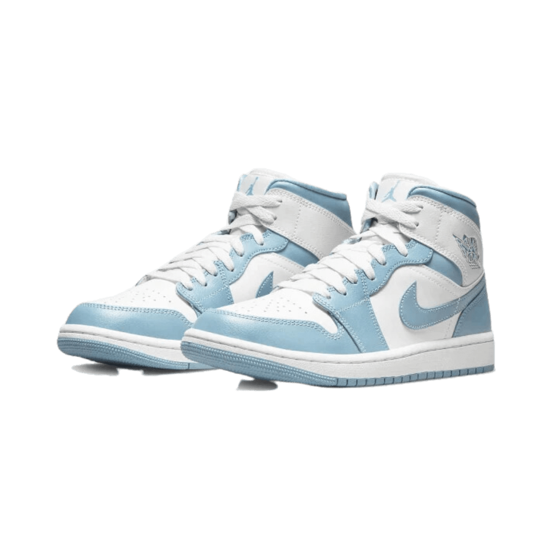 Stijlvolle Air Jordan 1 Mid UNC (2022) sneakers in wit en lichtblauw op een groene achtergrond. De klassieke basketbal-silhouet met opvallende kleurcombinatie maakt deze sneakers tot een modieus statement-item.