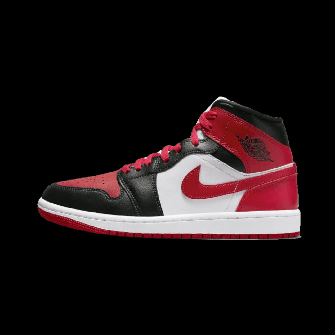 Rode en zwarte Nike Air Jordan 1 Mid sneakers met wit detail op een groene achtergrond