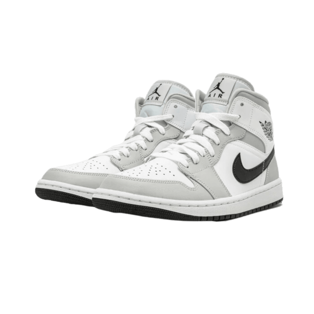 Elegante Air Jordan 1 Mid sneakers in licht grijze kleurstelling. De klassieke basketbalschoenen met kenmerkend Nike swoosh-logo en voorzien van stevige zool.