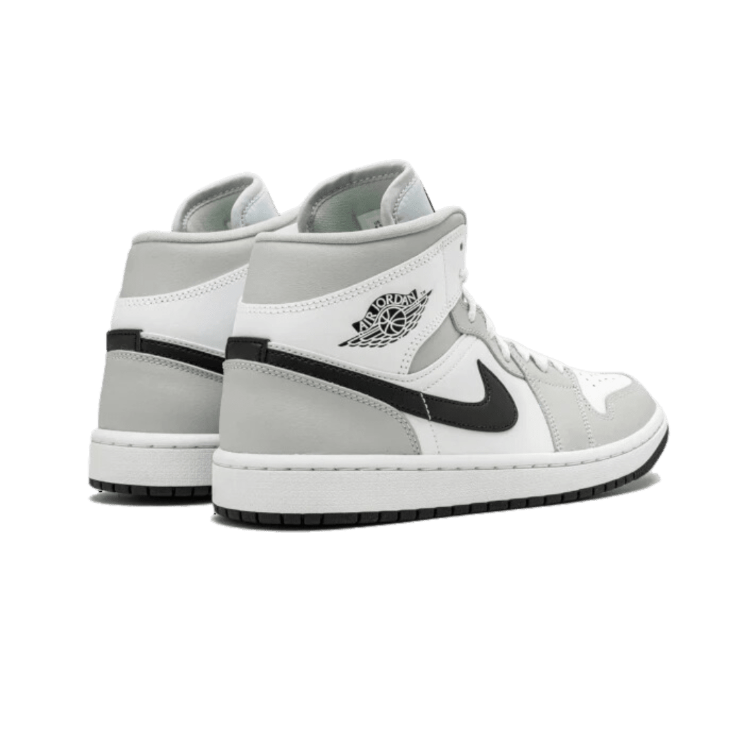 Exclusieve Air Jordan 1 Mid White Light Smoke Grey sneakers op een donkergroene achtergrond, met herkenbare Nike-branding en een strak minimalistisch ontwerp.