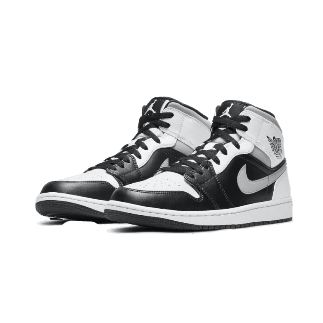 Zwart-witte Nike Air Jordan 1 Mid sneakers met klassieke look op groene achtergrond
