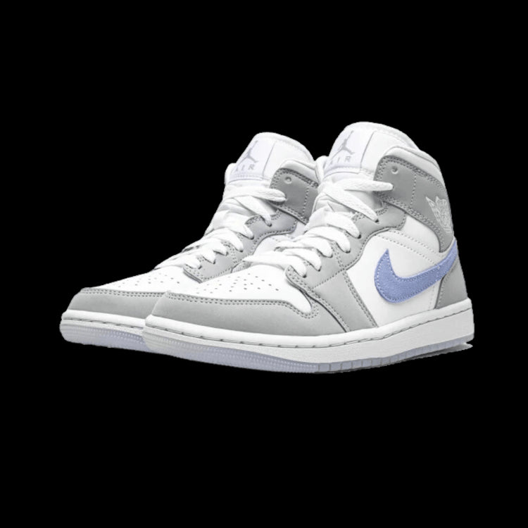 Witte, grijze en blauwe Nike Air Jordan 1 Mid sneakers met een klassiek ontwerp op een groene achtergrond.
