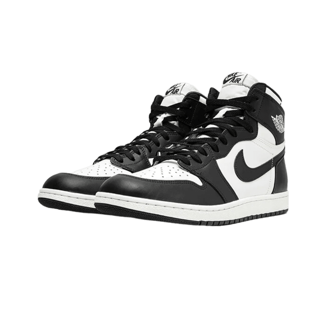 Zwart-witte Nike Air Jordan 1 Retro High 85 OG sneakers op een groene achtergrond