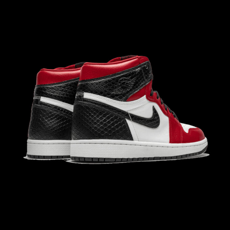 Rode en zwarte Air Jordan 1 Retro High Satin Snake sneakers op een groene achtergrond