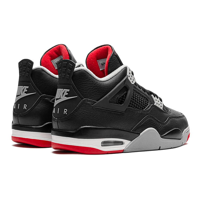 Zwarte en rode Air Jordan 4 Retro Bred Reimagined sneakers op een groene achtergrond. De sneakers hebben een klassiek ontwerp met leer en mesh materialen, rode accenten en de kenmerkende Nike Air logo. Dit is een premium basketbalschoen met goed demping en stabiliteit.