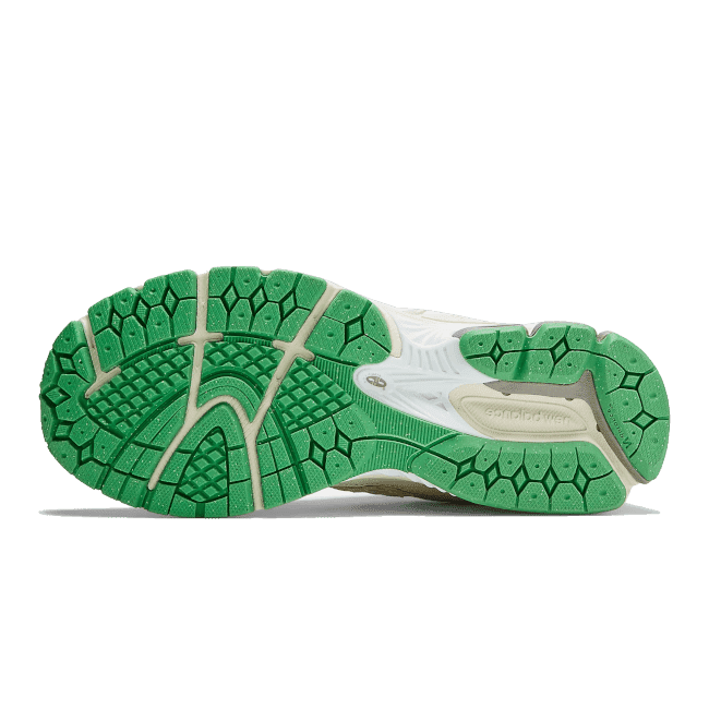 Groene sneakerlogo op witte New Balance 2002R GANNI Turtledove sneaker, weergeven op een groene achtergrond.