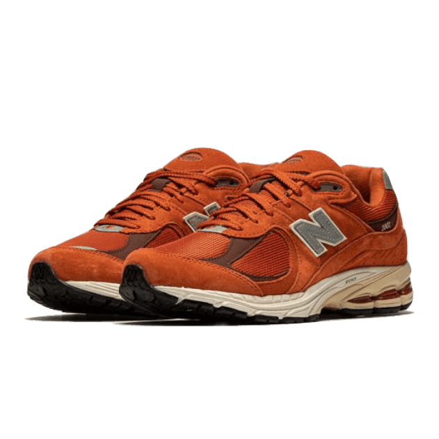 Oranje New Balance 2002R Rust Oxide sneakers op groene achtergrond