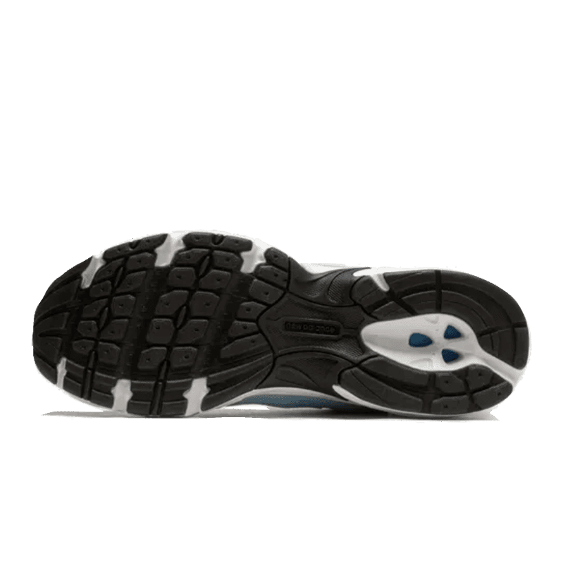 Nieuwe Balance 530 Blue Haze sneakers op een donkergroene achtergrond. De schoenen hebben een zwart-witte rubberen zool met een grappig gestructureerd patroon voor extra grip. De bovenkant van de sneakers heeft een blauwe kleur met subtiele accenten.