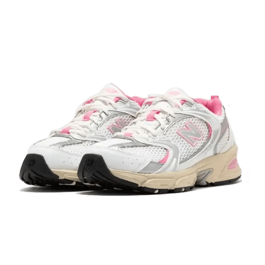 Witte en roze New Balance 530-sneakers op een groene achtergrond