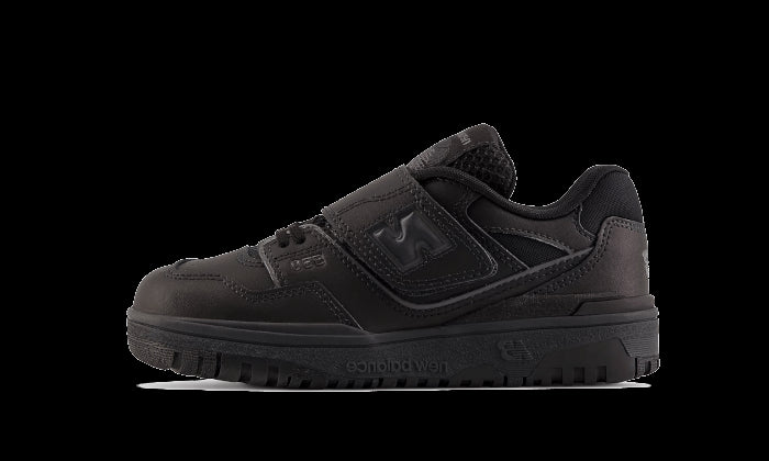 Zwarte New Balance 550 Strap sneakers voor kinderen (PS) met een sluitriempje op een donkergroene achtergrond.