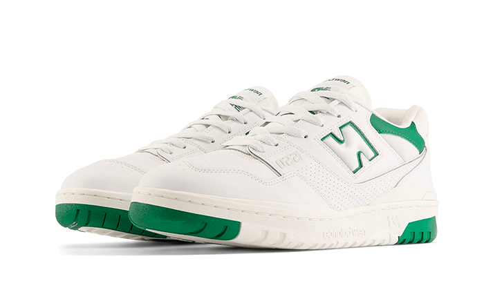 Nieuwe Balance 550-sneakers in wit en klassiek groen op een effen groene achtergrond. De sportieve en minimalistische sneakers hebben een goed zichtbaar New Balance-logo op de zijkant en een groen accent op de zool voor een moderne, trendy uitstraling.