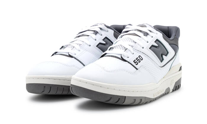 Witte New Balance 550 sneakers met donkergrijze accenten. Deze klassieke sneakers hebben een laag profiel en een premium lederen bovenwerk, perfect voor een moderne en stijlvolle look.