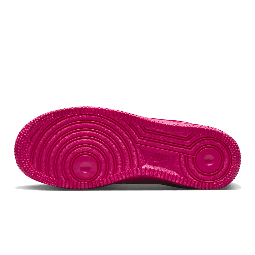 Roze Nike Air Force 1 Low '07 Fireberry sneaker met opvallende textuur en vormgeving geplaatst tegen een groene achtergrond.