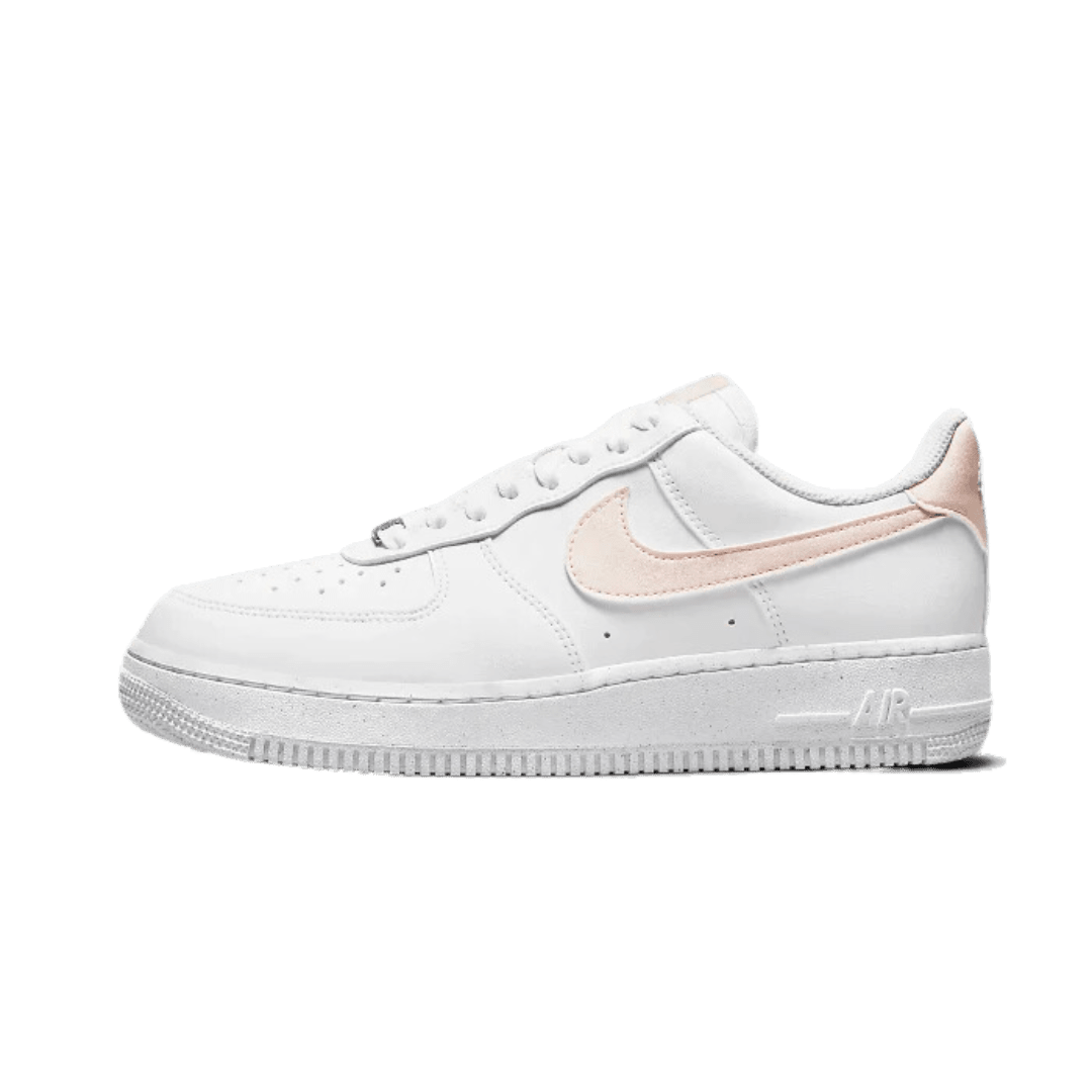 Witte Nike Air Force 1 Low Next Nature sneakers met zachte roze accenten op een groene achtergrond