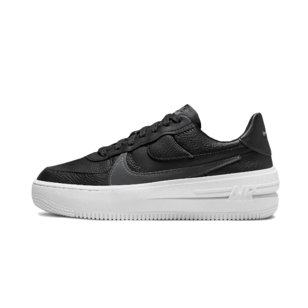 Zwarte Nike Air Force 1 Platform sneakers op een strak groene achtergrond