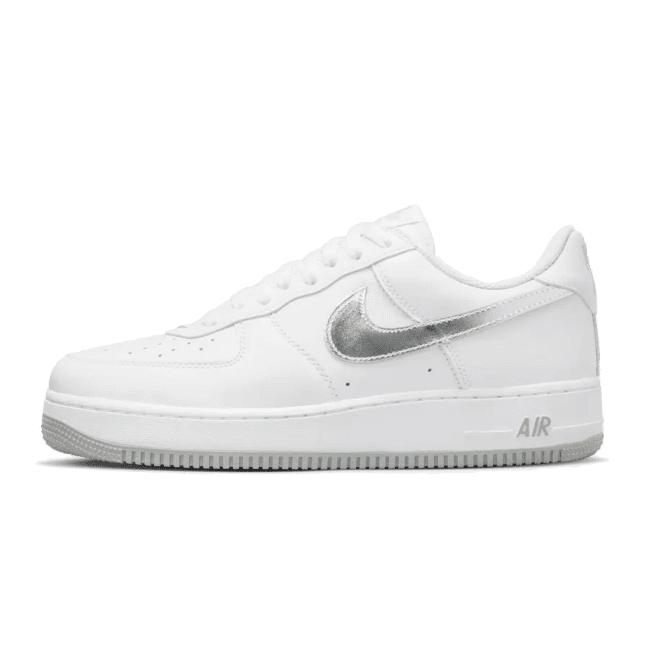 Witte Nike Air Force 1 Low Retro sneakers met metallic zilveren accenten op een effen groene achtergrond