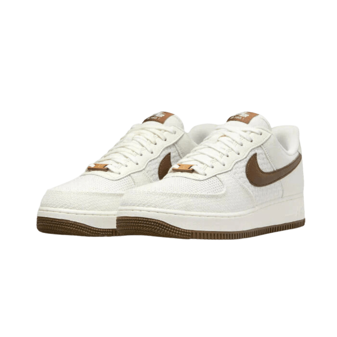Witte leren Nike Air Force 1 Low SNKRS Day 5th Anniversary sneakers op een groene achtergrond.