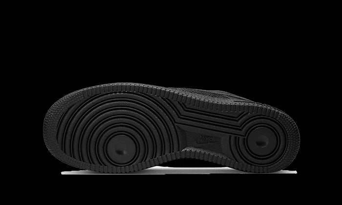 Exclusieve Nike Air Force 1 Low Slam Jam sneakers in zwart tegen een donkergroen oppervlak. Deze iconische lage sneakers hebben een robuuste zool met een opvallend patroon en een gestroomlijnd ontwerp.