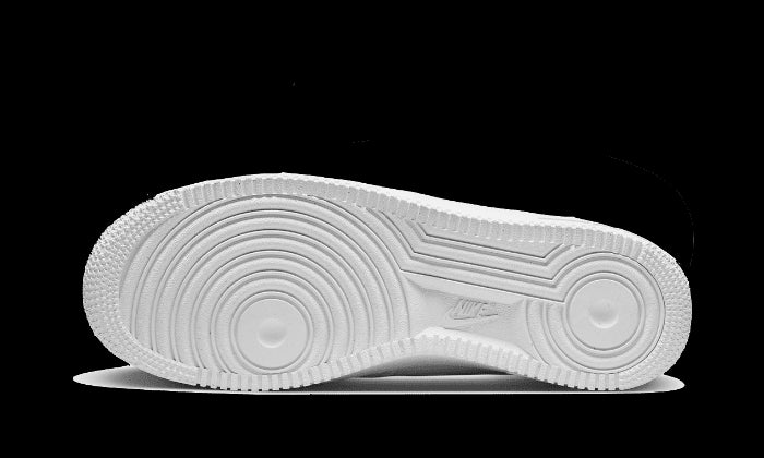 Klassieke Nike Air Force 1 Low sneakers met een stencil-swoosh logo op de zijkant tegen een groene achtergrond.