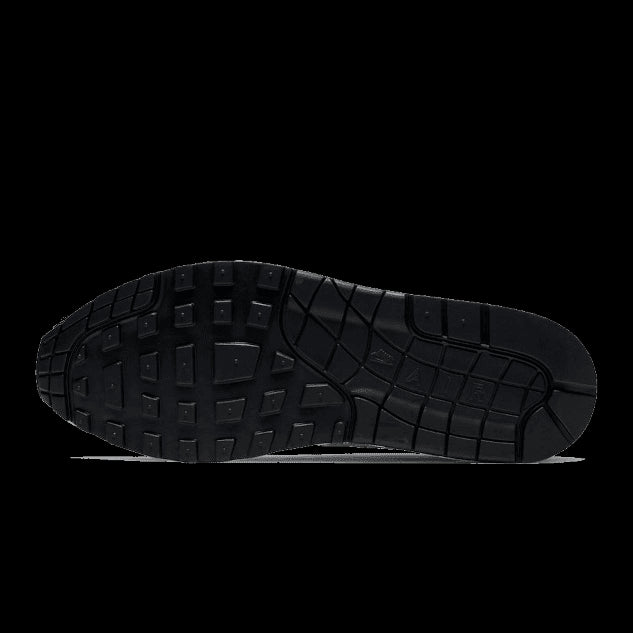 Zwarte Nike Air Max 1-sneakerzool met opvallend patroon tegen een groene achtergrond
