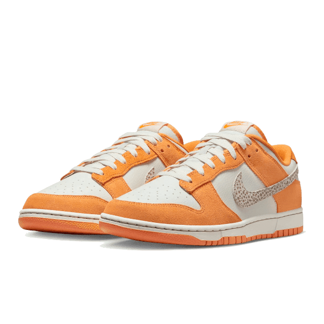 Oranje-witte Nike Dunk Low AS Safari Swoosh Kumquat sneakers op een effen groene achtergrond.