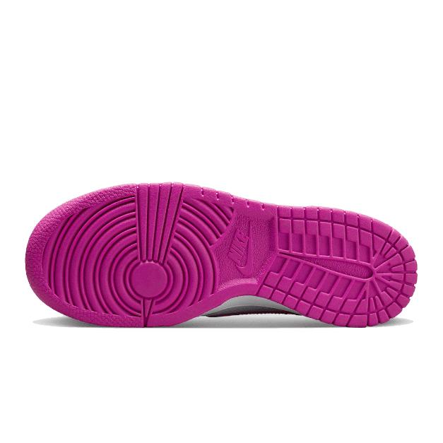 Fel roze Nike Dunk Low sneakers op groene achtergrond