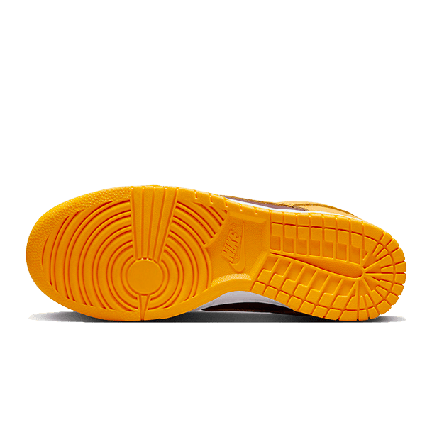 Oranje Nike Dunk Low Arizona State sneakers met gedetailleerd geribbeld zool op een groene achtergrond.
