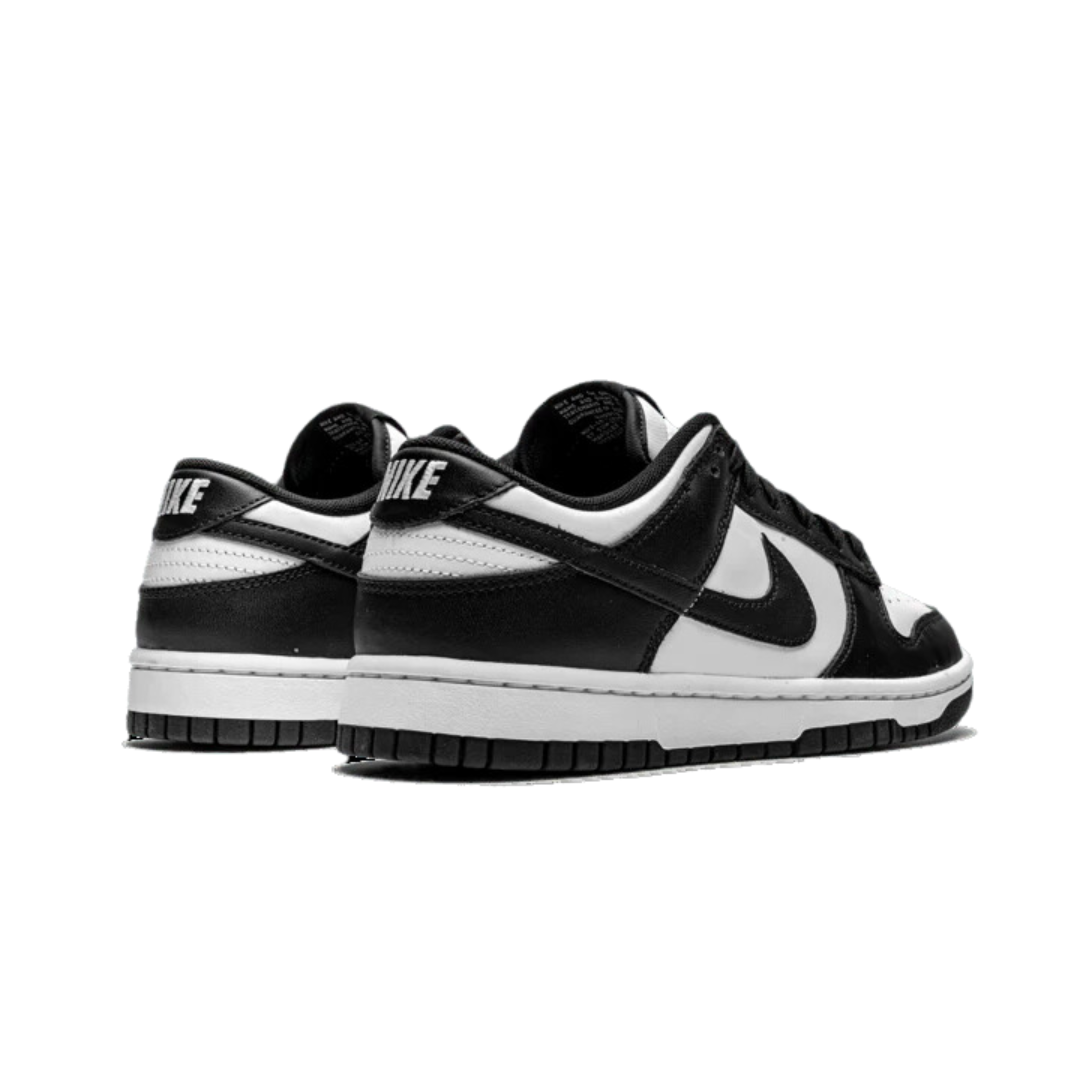 Klassieke Nike Dunk Low sneakers in zwart en wit, met het kenmerkende Nike-logo prominent aanwezig. Deze iconische sportschoenen combineren stijl en functionaliteit en zijn perfect voor dagelijkse dracht.
