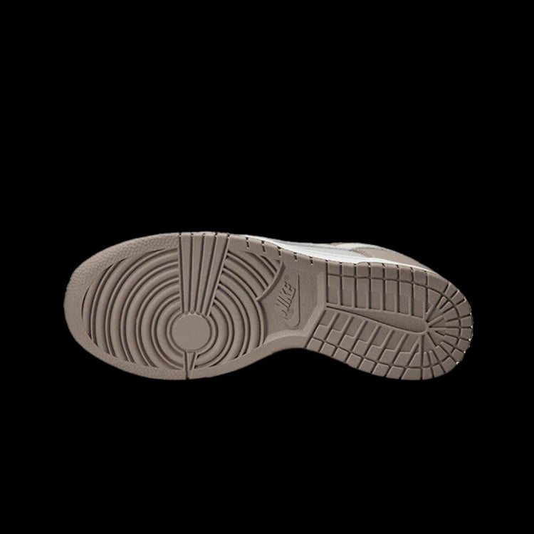 Bone beige Nike Dunk Low sneakers met een gedetailleerde zool en schokabsorberende eigenschappen op een effen zwarte achtergrond.