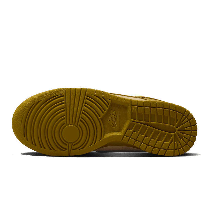 Gele Nike Dunk Low sneaker met bruin/oranje accenten op een groene achtergrond