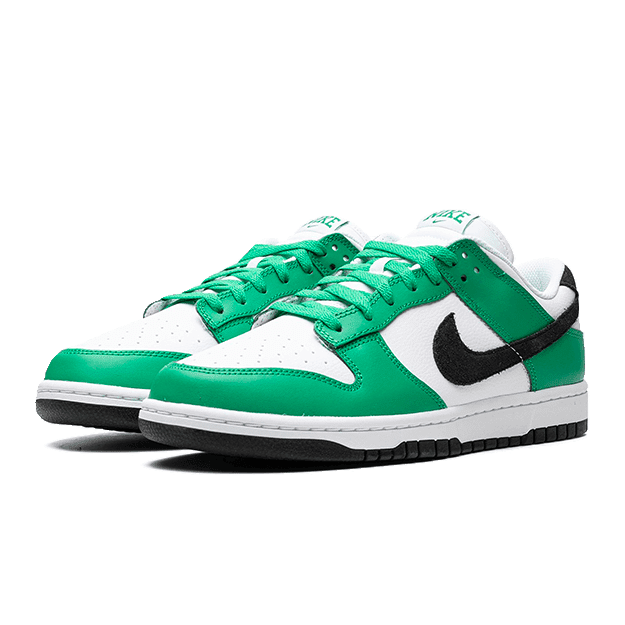 Sportieve groene en witte Nike Dunk Low Celtics sneakers op een groene achtergrond. Deze klassieke sneakers hebben een wit lederen bovenwerk met groen suède accenten en een zwart Nike Swoosh logo. De dikke schuimrubberen zool biedt comfort en grip.