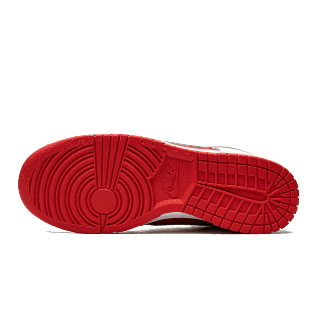 Rode Nike Dunk Low Championship sneakers met een opvallend gestreept zoolpatroon op een groene achtergrond