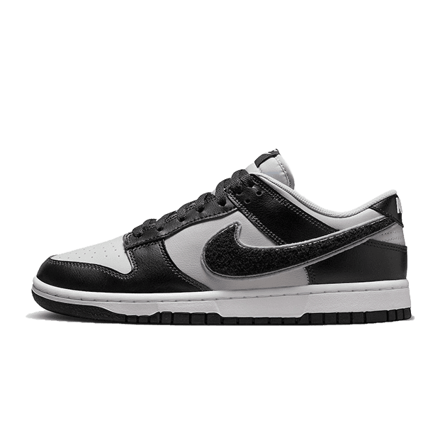 Zwarte en grijze Nike Dunk Low Chenille Swoosh sneakers op een groene achtergrond