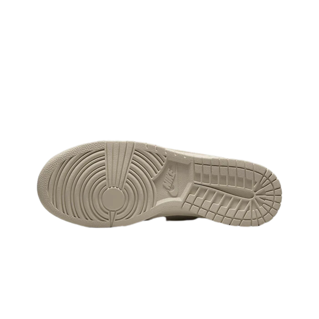 Goed gefotografeerde close-up van de zool en hiel van een paar Nike Dunk Low Denim Light Orewood Brown sneakers. Het product komt goed tot zijn recht, met duidelijk zichtbare details zoals de geribbelde rubberen zool en het denim bovenwerk in een lichtbruine tint.