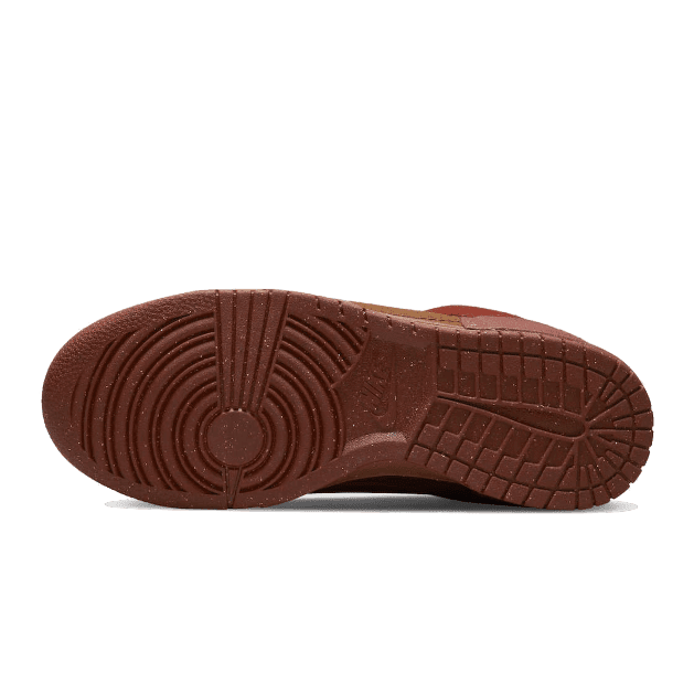 Bruine Nike Dunk Low Disrupt 2 Desert Bronze sneakers met een robuuste zool op een groene achtergrond
