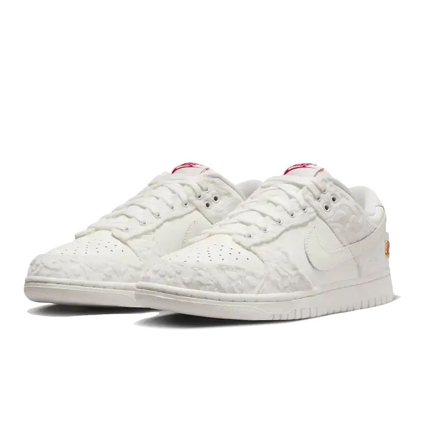 Witte Nike Dunk Low sneakers met roze accenten. De sneakers zijn voorzien van een gestructureerd bovendeel en een sportieve, comfortabele zool. De schoenen maken deel uit van de "Give Her Flowers"-collectie.