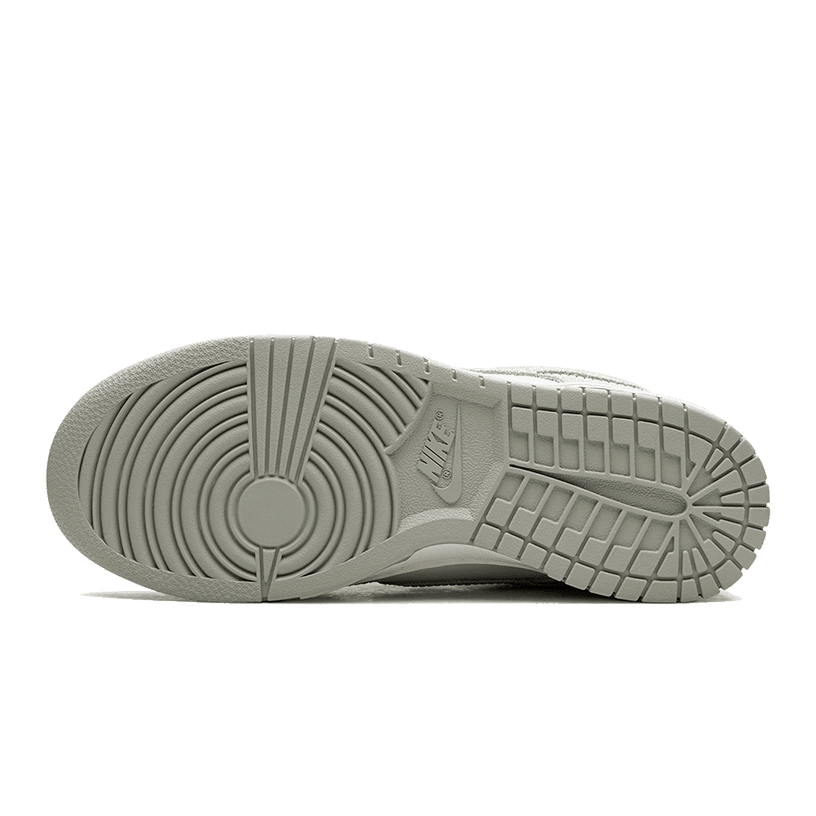 Nike Dunk Low Grey Corduroy - Stevige, geribbelde zool van grijze sneaker op groene achtergrond