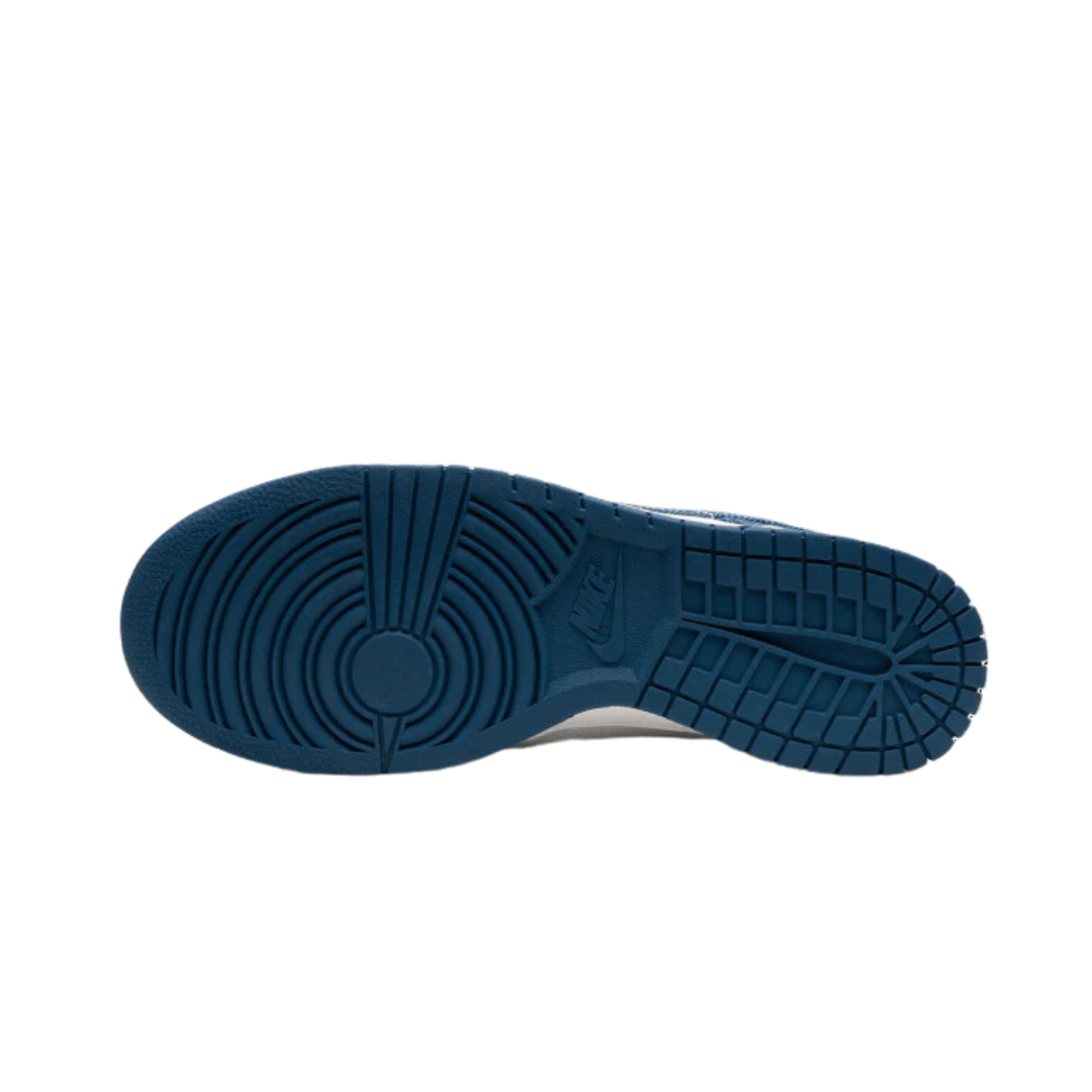 Blauwe Nike Dunk Low Industrial Blue Sashiko sneakers met een gestructureerd zoolpatroon op een zwarte achtergrond