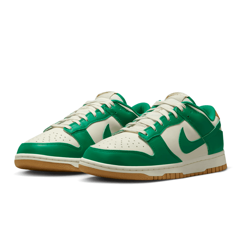 Groen-witte Nike Dunk Low Malachite University Goud sneakers op een groene achtergrond
Klassieke sneakers met malachiet groene en witte kleuren, voorzien van een sierlijk Nike logo