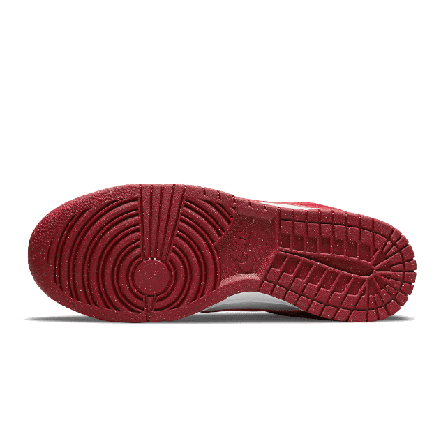 Nike Dunk Low Next Nature Gym Red sneakers met een rood, gestructureerd zoolprofiel op een groene achtergrond.